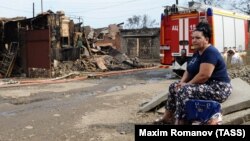 A local resident sits at the site of the fire in central Rostov that damaged or destroyed 123 residential buildings and killed one man. 