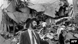 A man walks over the rubble left after a bomb exploded at the Argentinian Israelite Mutual Association (AMIA) in Buenos Aires, 18 July 1994