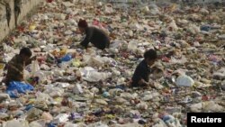 Children look for recyclable plastic in a canal in Peshawar, Pakistan, January 18, 2016.