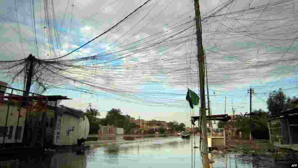 Tangled electrical wires are seen over a rain-flooded street in the Iraqi capital, Baghdad. (AFP/Sabah Arar)