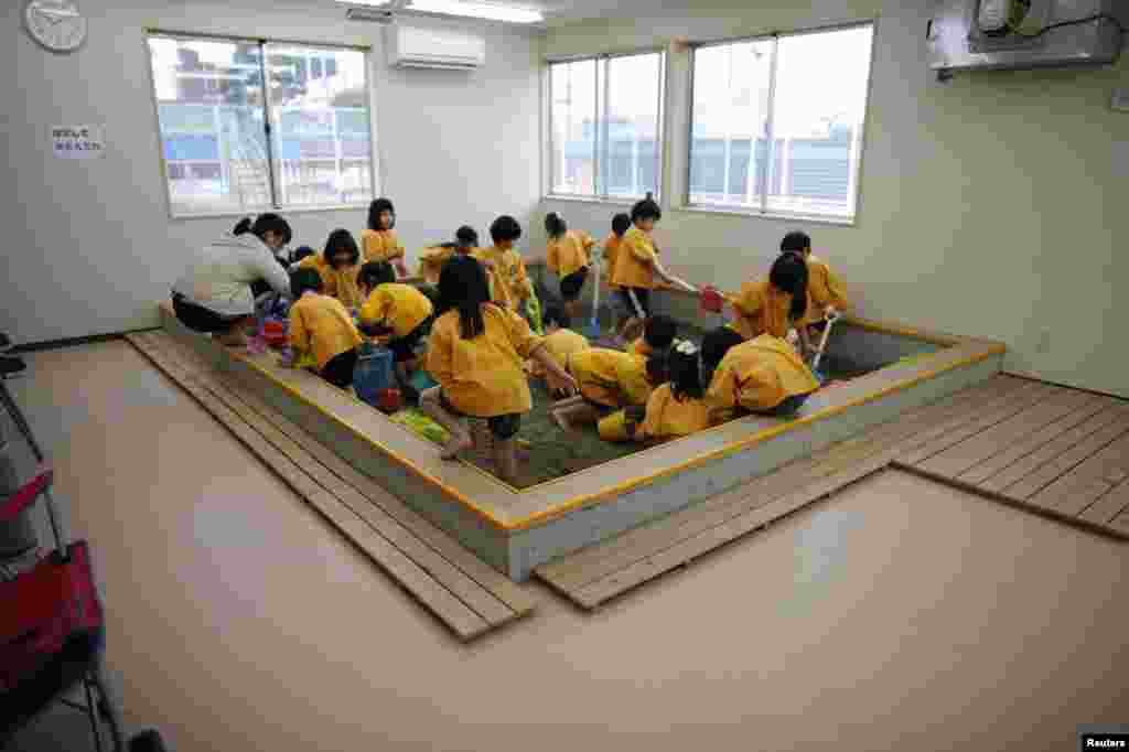 Children play in an indoor sand box.