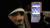 Ирандық әйелдің қолындағы мобильдік телефонда Иранның ең жоғарғы дінбасы – аятолла Хаменеи мен Иран Ислам Республикасының негізін қалаған аятолла Хомейни бейнеленген. Теһрандағы оппозиция наразылығы. Желтоқсан, 2009 жыл.