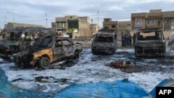 A picture taken with a mobile phone shows burnt vehicles at the scene of a blast from a massive car bomb, which killed scores of people in Baghdad on February 16. 