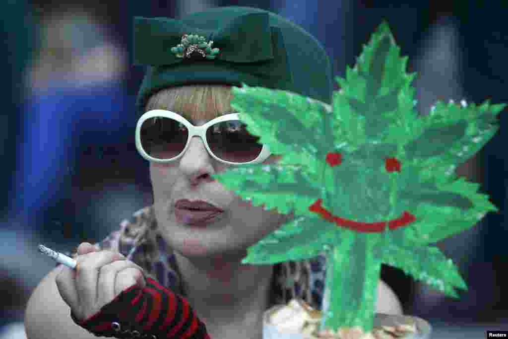 A woman smokes a cigarette while holding a cut-out of a cannabis leaf during a rally in Tbilisi, Georgia in support of easing penalties for marijuana possession. (Reuters/David Mdzinarishvili)
