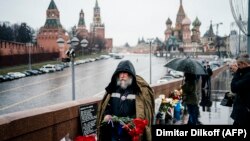 An elderly man carrying red carnations walks to lay flowers at the site where late opposition leader Boris Nemtsov was fatally shot on a bridge near the Kremlin, in central Moscow on February 27.