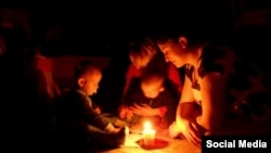 Një familje duke ndriçuar dhomën me një qiri. Fotografi nga arkivi.