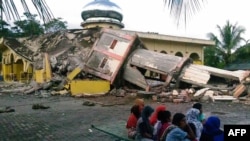 شماری از ساکنان استان آچه اندونزی کنار ویرانه‌های یک مسجد که بر اثر زلزله ۶.۵ ریشتری تخریب شده است