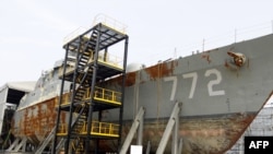 South Korean navy personnel stand guard next to the wreckage of the salvaged naval vessel Cheonan.