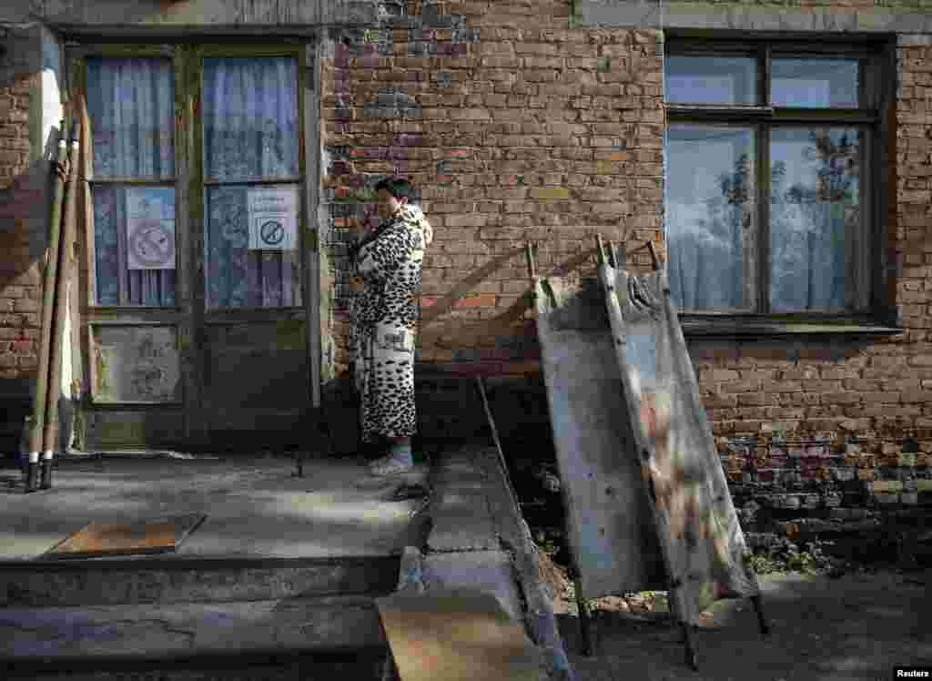 A woman smokes next to blood-stained stretchers placed to dry in the sun at a hospital in Schastya, near the eastern Ukrainian town of Luhansk. (Reuters/David Mdzinarishvili)