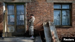 A woman smokes next to blood-stained stretchers placed to dry in the sun at the hospital in Shchastya in October 2014.