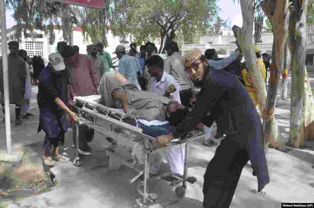 People rush an injured passenger to a hospital in Rahim Yar Khan, July 11, 2019.