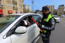 Карантин кезінде жүргізушілерді тексеріп жатқан полиция қызметкері. Баку, мамыр айы 2020 жыл.