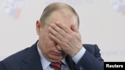 Prime Minister Vladimir Putin covers his face during a conference of the Russian Union of Industrialists and Entrepreneurs in Moscow on February 9.