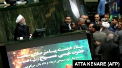 Iranian President Hassan Rouhani (Left) addresses parliament in Tehran on December 25, 2018 as he presents his government's 2019-2020 budget, with a notice below his podium providing Christmas greetings to Christians.