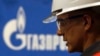 Un muncitor care lucrează pentru Gazprom surpins lângă logo-ul companiei
