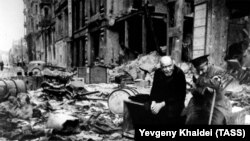 Kor kişi (sağda) bələdçi ilə. Şəkil 1945-ci ildə dağılmış Berlin küçəsində çəkilib. Khaldei kişidən almanca onların haradan gəldiklərini soruşub. Kor kişi belə cavab verib: "Biz daha bilmirik. Biz haradan gəldiyimizi və haraya getdiyimizi bilmirik".