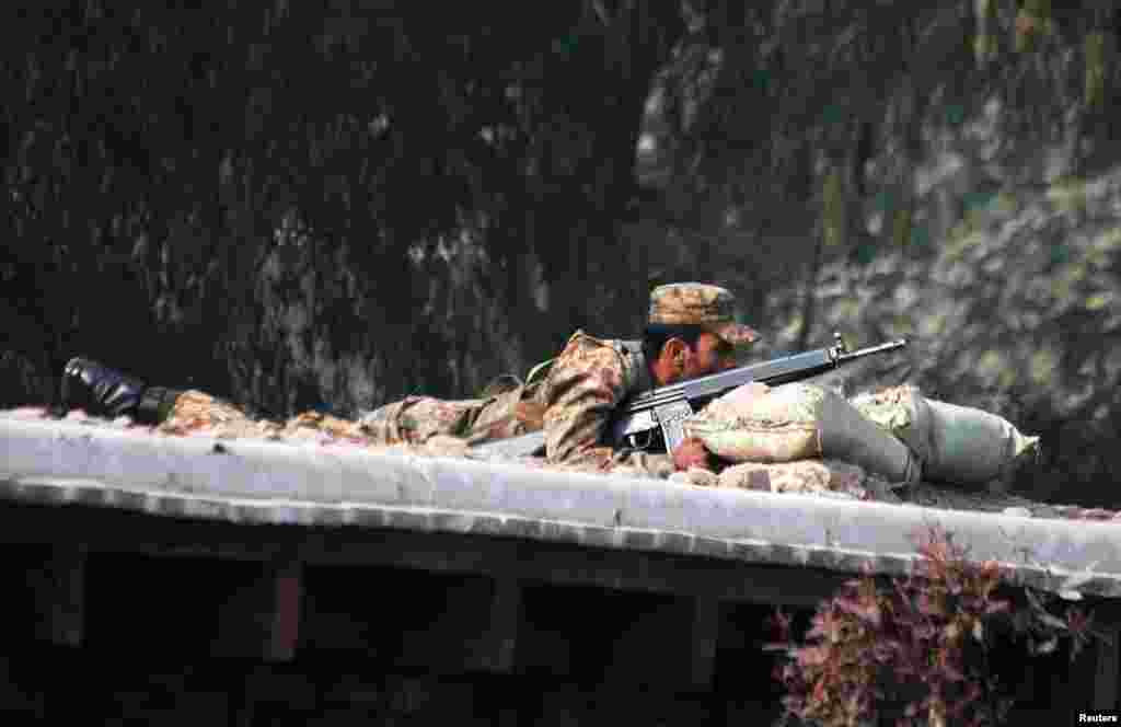 A Pakistani soldier takes up a position above a road near the military school.