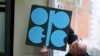 A worker attaches a poster of the Organization of the Petroleum Exporting Countries, OPEC, at their headquarters in Vienna, Austria, Wednesday, Nov. 29, 2017.