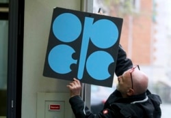 Рабочий прикрепляет плакат Организации стран-экспортеров нефти (ОПЕК), в их штаб-квартире в Вене, ноябрь 2017 год