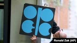 A worker attaches a poster of the Organization of the Petroleum Exporting Countries at its headquarters in Vienna.