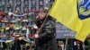 UKRAINE -- An activist of Maidan holding a flag, makes the sign of the cross as he pays a tribute at the Maidan activists memorial also called the "Heroes of the Heavenly Hundred", referring to the people killed during the anti-government demonstration of
