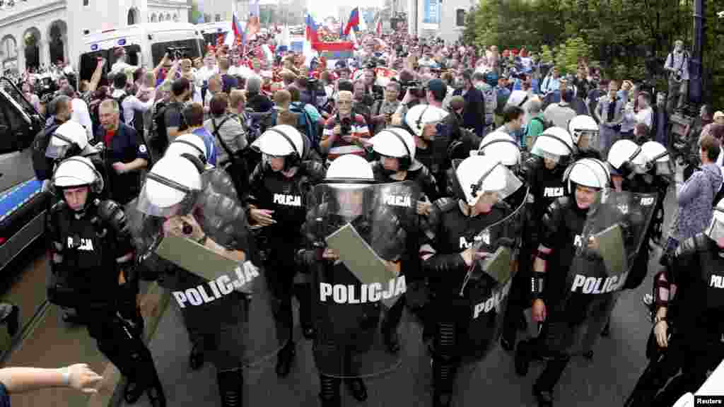 Russian soccer fans walk, protected by Polish riot police in Warsaw.