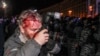 Ukraine -- Wounded Reuters photographer Gleb Garanich, who was injured by riot police, takes pictures as riot police block protesters during a scuffle at a demonstration in support of EU integration on Independence Square in Kyiv, November 30, 2013