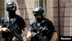 Armed police officers stand outside a residential property near to where a man was arrested in the Chorlton area of Manchester, Britain 