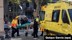 Спасатели и полицейские увозят пострадавших с месте наезда фургона на толпу. Барселона, 17 августа 2017 года. 