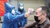 امدادگران در حال اندازه‌گیری دمای بدن یک شهروند چینی در ووهان، مرکز استان هوبی