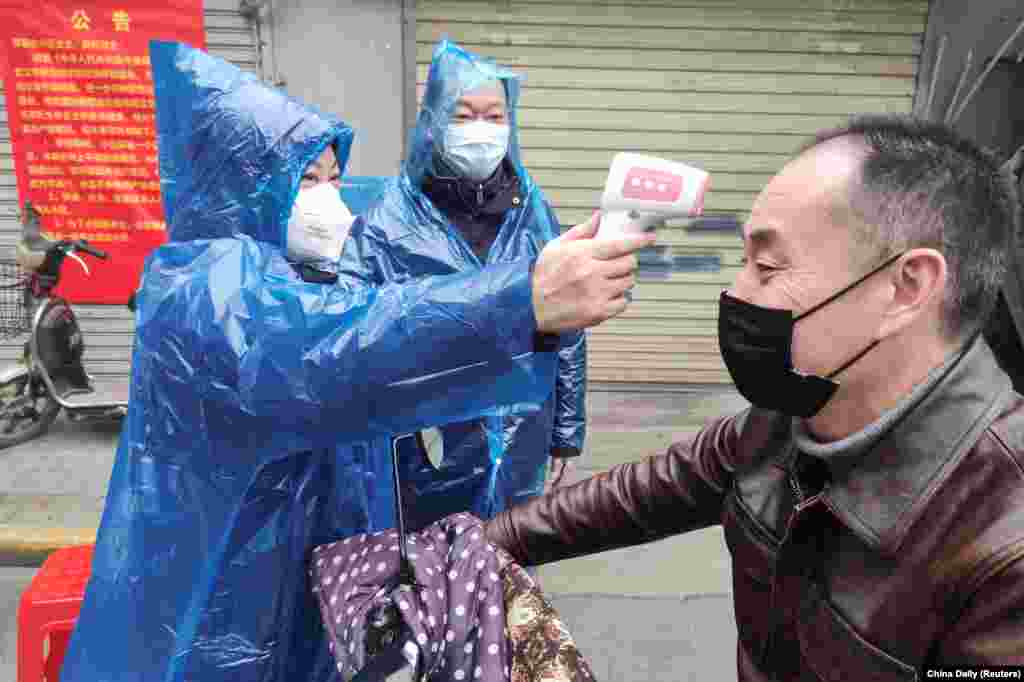CHINA -- A worker takes body temperature measurement of a man at the entrance to a residential compound following an outbreak of the new coronavirus in Wuhan, Hubei province, February 1, 2020