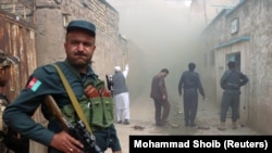 FILE: An Afghan police officer stands guard outside a Shi'ite mosque after a suicide bomb attack in Herat on March 25