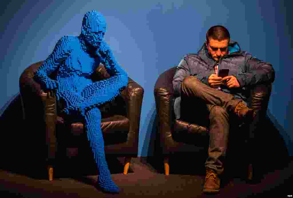 A visitor sits next to an artwork titled Blu Guy Sitting, made from 21,682 Lego bricks by U.S. artist Nathan Sawaya in Moscow. (epa/Sergei Ilnitsky)