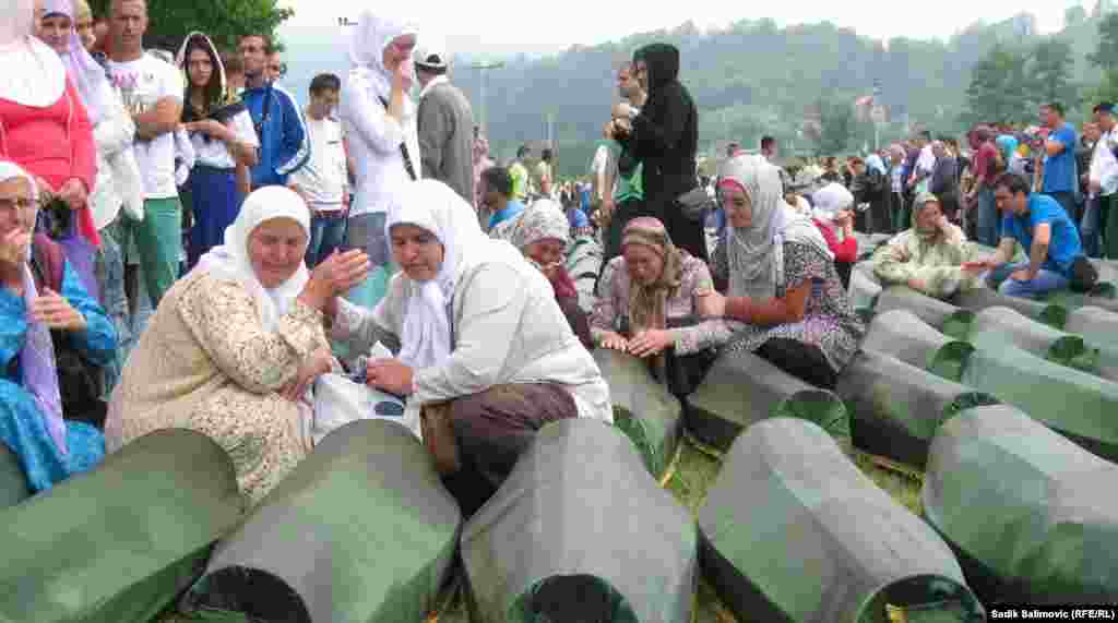 Bosnian women cry over the coffins of relatives, set to be reburied in Potocari, near Srebrenica.