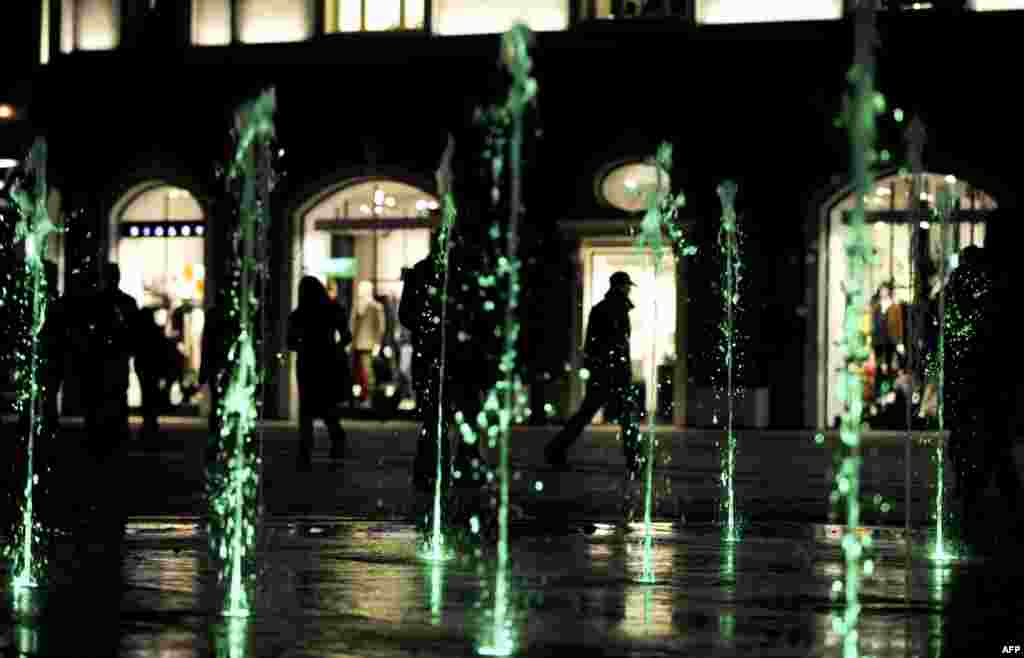 Pedestrians walk past a colored fountain in the center of Pristina, Kosovo. (AFP/Armend Nimani)