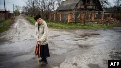 Пожилая женщина на безлюдной дороге недалеко от аэропорта Донецка. Апрель 2015 года.