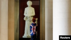 A boy stands in front of a statue of former British Prime Minister Margaret Thatcher on display in the Guildhall Art Gallery in London.