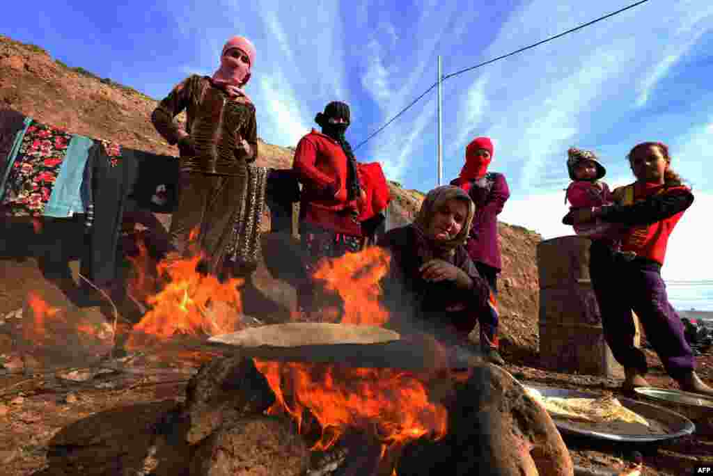 Группа женщин из числа иракских езидов готовит хлеб в лагере для перемещенных лиц в курдском городе Дахук, 14 января. Многие езиды были вынуждены оставить места своего проживания из-за столкновений между членами радикальной группировки &quot;Исламское государство&quot; (запрещена в России) и бойцами проправительственных формирований пешмерга.