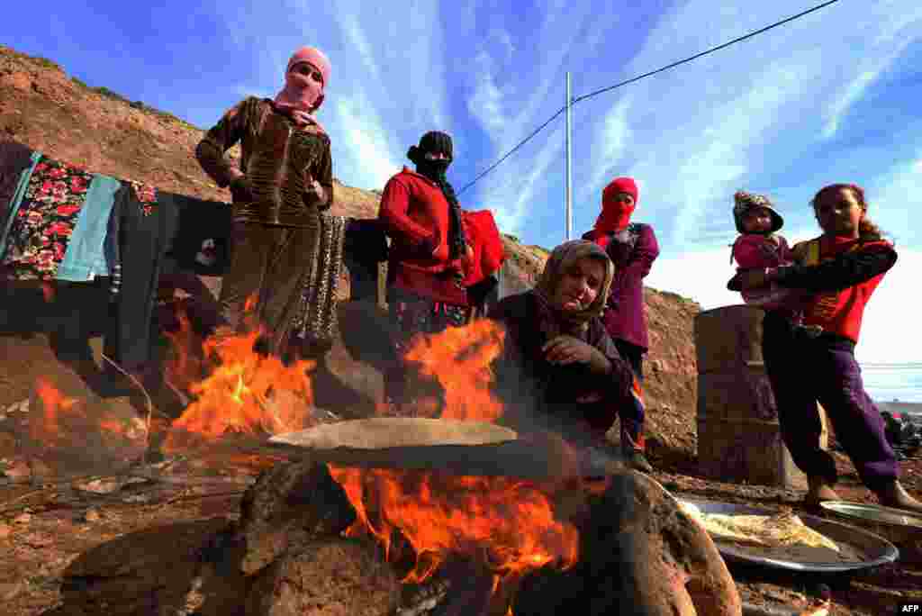 Displaced Iraqis from the Yazidi community wait for bread to bake at Dawodiya camp for internally displaced people in the Kurdish city of Dohuk on January 14, 2015. The Yazidis fled violence between Islamic State jihadists and Peshmerga fighters in the northern town of Sinjar in Iraq's northern autonomous Kurdistan region. Tens of thousands of members of the Yazidi religious minority were trapped by IS on Mount Sinjar for days in the searing August heat in a first siege by IS that sparked fears of genocide. (AFP/Safin Hamed)
