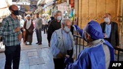 An Iranian official checks the temperature of visitors at the Shah Abdol-Azim shrine in the capital, Tehran, on May 25.