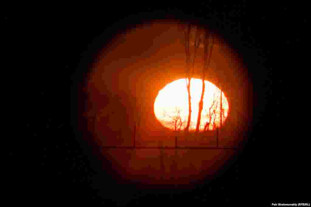 The rising sun is seen through a military scope from a Ukrainian army position near Zaytseve.