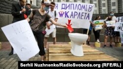 Protesters throw mock diplomas in a toilet placed in front of a government building in Kyiv. 