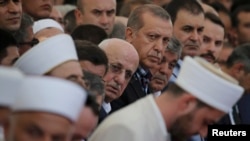 A group of imams bow their heads next to Turkish President Recep Tayyip during a funeral service for victims of the thwarted coup in Istanbul.