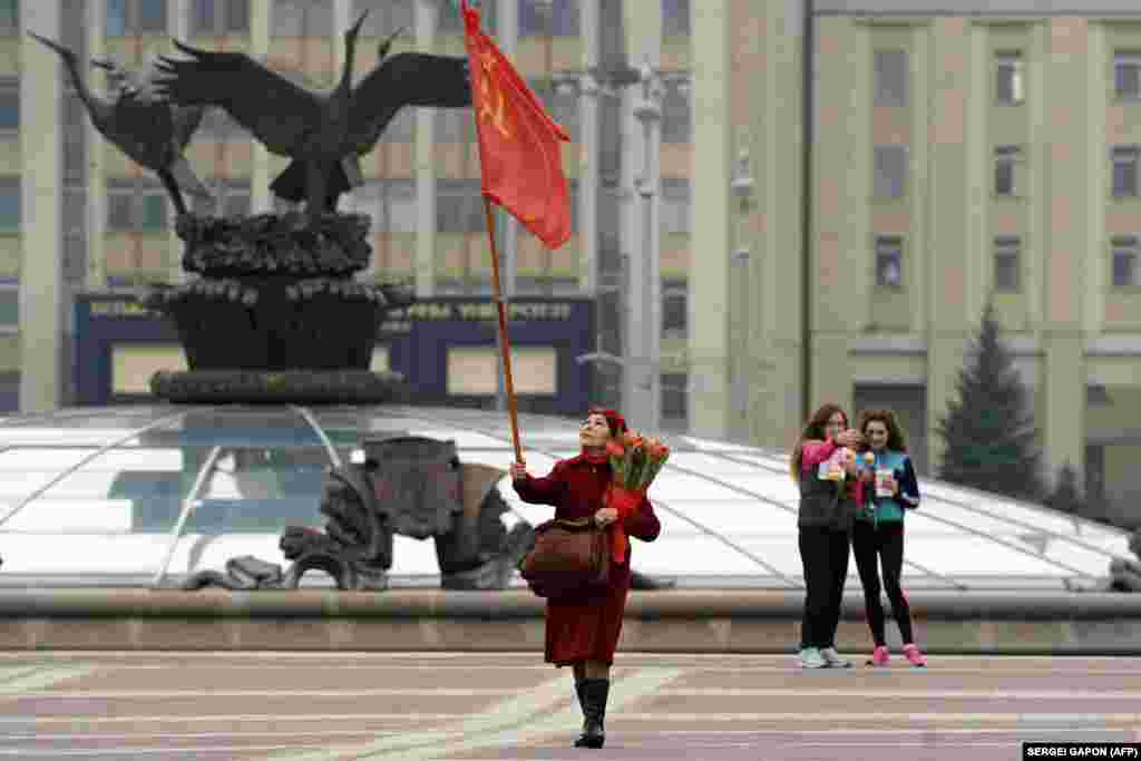 An elderly woman carries a Soviet flag on Independence Square as she celebrates International Women's Day in Minsk on March 8. (AFP/Syarhey Gapon)