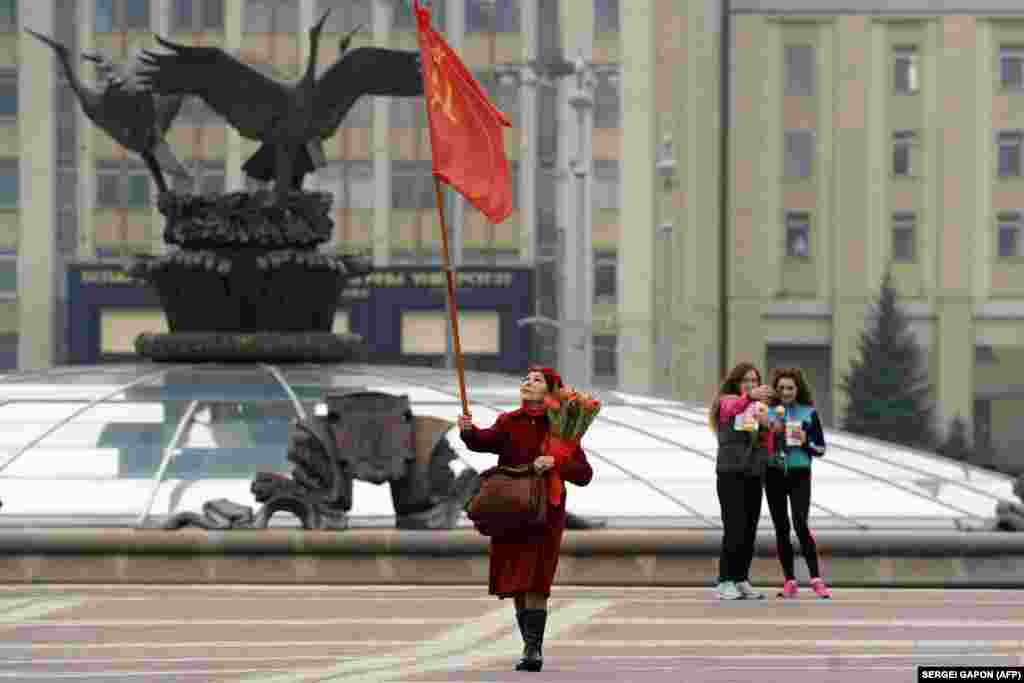 An elderly woman carries a Soviet flag on Independence Square as she celebrates International Women&#39;s Day in Minsk on March 8. (AFP/Syarhey Gapon)