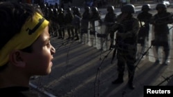 A boy, with supporters of the Muslim Brotherhood and ousted Egyptian President Muhammad Morsi, stands in front of army soldiers and riot police, during a protest in Cairo on October 4.