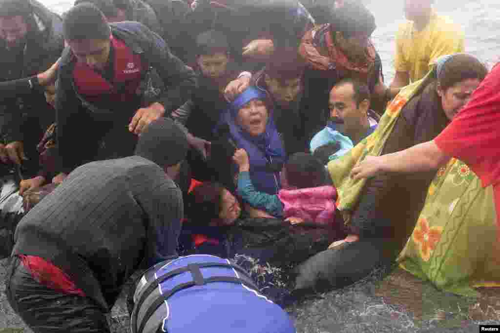 Refugees and migrants struggle to get off an overcrowded dinghy as they arrive on the Greek island of Lesbos after crossing part of the Aegean Sea from the Turkish coast. A woman and a child drowned off Lesbos after their boat sank, although 45 other people were rescued, police said on September 30. (Reuters/Dimitris Michalakis)