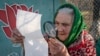 Възрастна жена разглежда бюлетината в избирателна секция близо до Донецк.