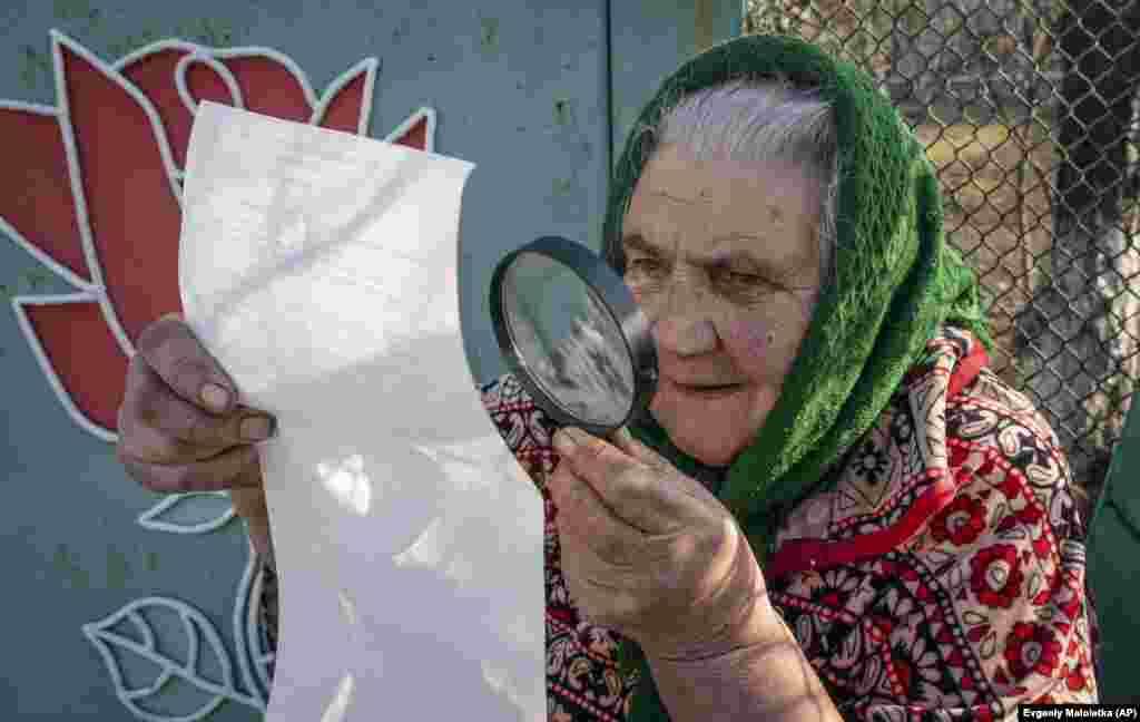 An elderly woman examines her ballot paper in Maryinka, near Donetsk, eastern Ukraine. (AP/Evgeniy Maloletka)