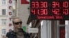A woman passes by a sign displaying ruble exchange rates in Moscow. The Russian currency recently fell to its lowest level against the US. dollar in almost five years. (file photo)